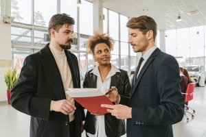 clients going over paperwork with product advisor in dealership
