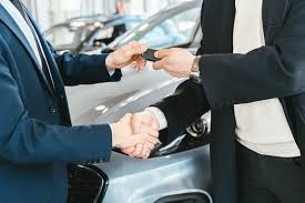 two people shaking hands and passing over vehicle keys