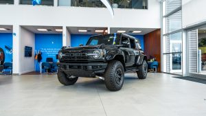 black 2025 ford bronco raptor sitting in bright showroom with blue background
