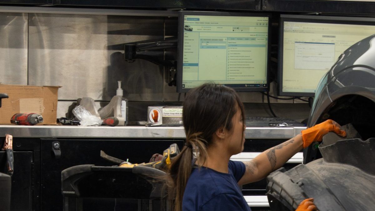 female automobile technician working on vehicle wheel
