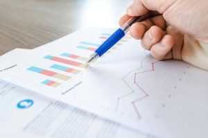 finance papers on table, hand holding pen over top