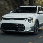 white 2026 kia niro ev driving down highway