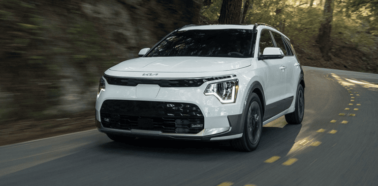 white 2026 kia niro ev driving down highway