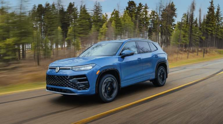blue 2026 Volkswagen Tiguan driving on highway with trees in the background